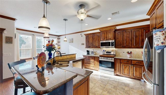 Kitchen featuring stainless steel appliances, visible vents, a ceiling fan, ornamental molding, and decorative backsplash | Image 21