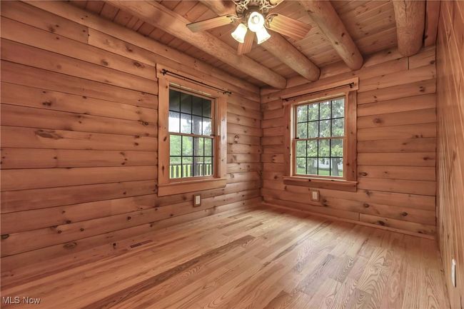 First floor guest bedroom with wood floors, walls and overhead ceiling fan and light | Image 12