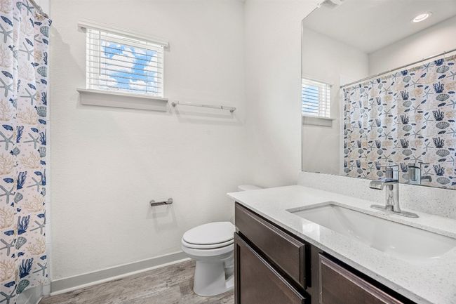 The second full bathroom, featuring a single vanity with quartz countertops, modern fixtures, and a shower/tub combo. | Image 21
