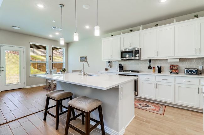 Kitchen featuring a sink, stainless steel appliances, light wood-style floors, backsplash, and recessed lighting | Image 15