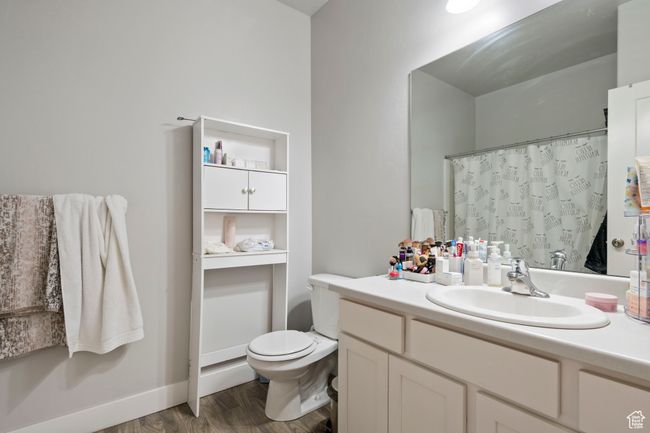 Bathroom featuring vanity, toilet, wood finished floors, a shower with shower curtain, and baseboards | Image 14