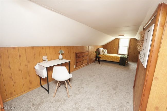 Carpeted bedroom with vaulted ceiling and wooden walls | Image 28
