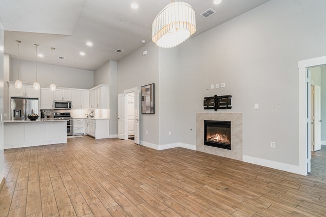 Living room with a towering ceiling, light wood-style flooring, a premium fireplace, baseboards, and recessed lighting | Image 9