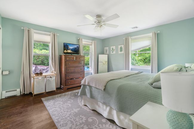 Bedroom featuring a baseboard heating unit, wood finished floors, and ceiling fan | Image 25