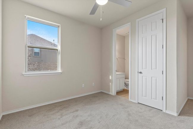 Unfurnished bedroom featuring light carpet, ensuite bathroom, and ceiling fan | Image 16