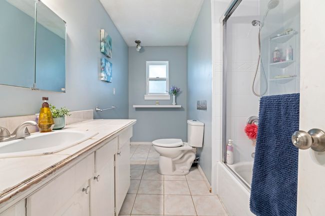 Bathroom with shower / bathtub combination, vanity, toilet, tile patterned floors, and baseboards | Image 21