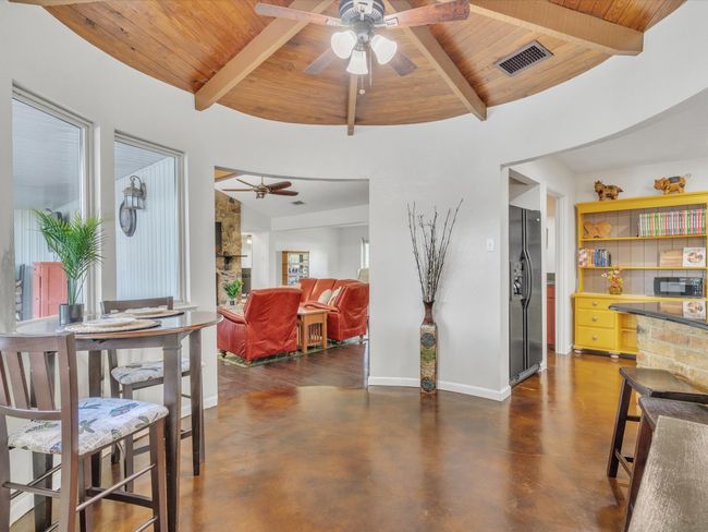 Dining space featuring wooden ceiling, ceiling fan, finished concrete flooring, and baseboards | Image 13