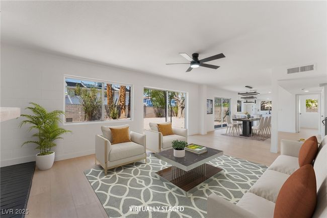 Living room featuring wood finished floors, ceiling fan, and concrete block wall | Image 7