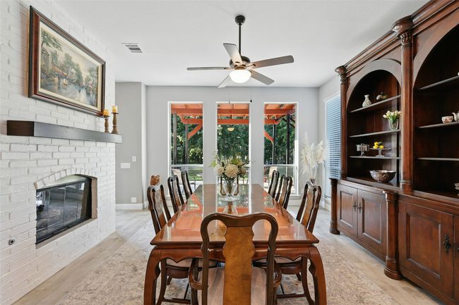 Dining area with ceramic tile wood-like floors, a ceiling fan, and a see through brick fireplace. Could be sitting area. | Image 10