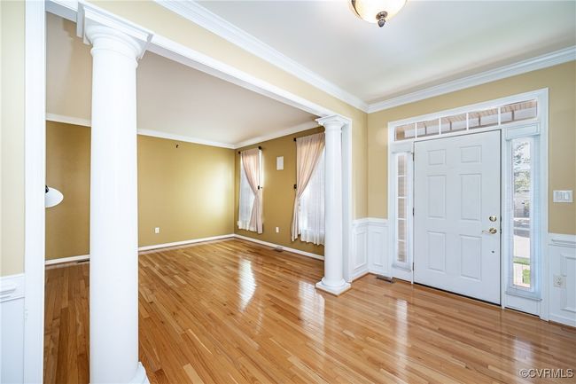 Foyer entrance with ornate columns, a wainscoted wall, light wood finished floors, and crown molding | Image 4