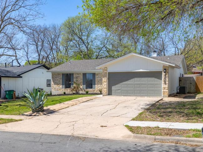 View of front facade with fence, concrete driveway, cooling unit, a garage, and stone siding | Image 8