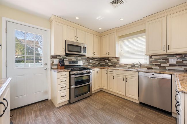 Kitchen featuring cream cabinets, visible vents, stainless steel appliances, and plenty of natural light | Image 4