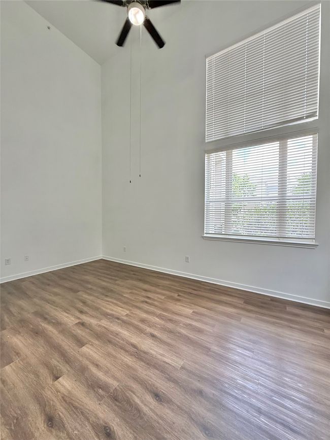 Empty room with a ceiling fan, baseboards, and wood finished floors | Image 11