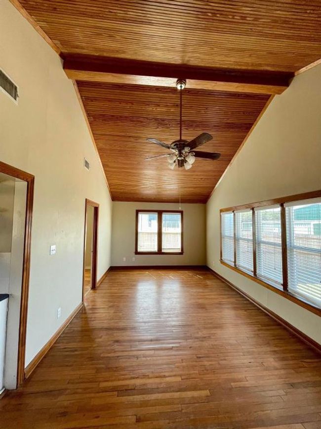 Unfurnished room with wood ceiling with exposed beams, ceiling fan, wood-type flooring, high vaulted ceiling, and baseboards | Image 7