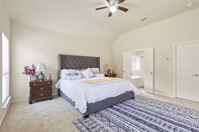 Bedroom featuring light carpet, baseboards, vaulted ceiling, ensuite bathroom, and a ceiling fan | Image 13