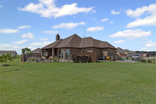 Rear view of property featuring a chimney, brick siding, and a shingled roof | Image 24