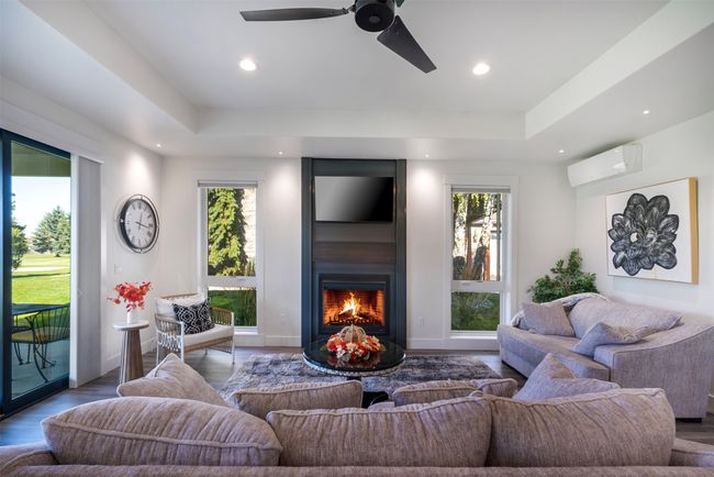 Living room featuring a raised ceiling, an AC wall unit, hardwood / wood-style floors, and ceiling fan | Image 10