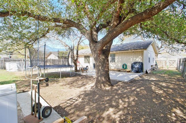 Rear view of house with a fenced backyard, a patio area, and a trampoline | Image 16