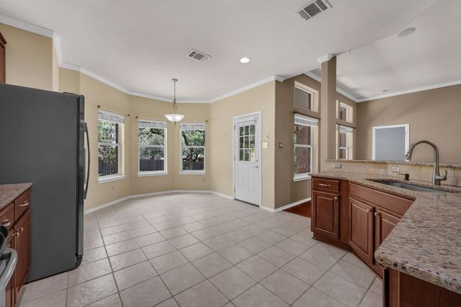 . The open-concept kitchen is a chef’s dream, offering granite countertops, stainless steel appliances, recessed lighting, cherry cabinetry with pull-out shelves, and a convenient breakfast bar overlooking the living room. | Image 10