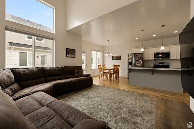 Living area featuring light wood-type flooring, a towering ceiling, recessed lighting, and a chandelier | Image 6