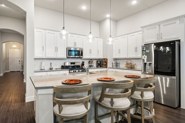 Kitchen with hanging light fixtures, can lights to enhance brightness large island with seating space, stainless steel appliances, quartz countertops | Image 4