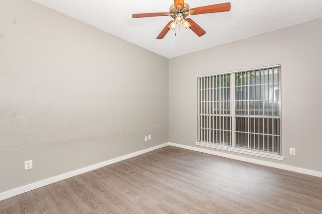 Spare room featuring baseboards, wood finished floors, a ceiling fan, and a textured ceiling | Image 15