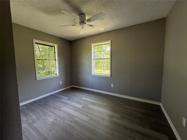 Unfurnished room featuring a ceiling fan, dark wood-type flooring, a textured ceiling, and baseboards. View 1 | Image 10