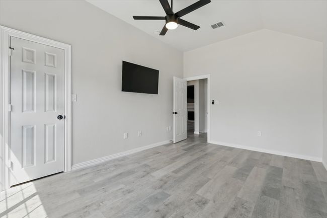 Empty room with a ceiling fan, vaulted ceiling, light wood finished floors, and baseboards | Image 19
