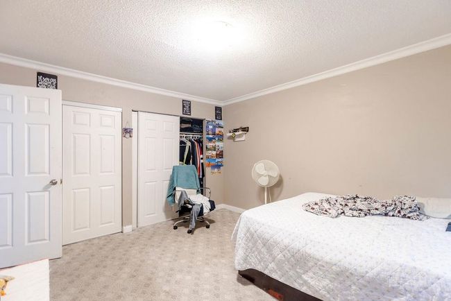 Bedroom with ornamental molding, carpet floors, and a textured ceiling | Image 13