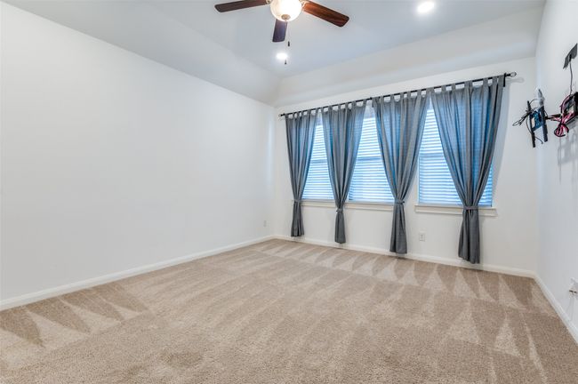 Spacious media game room filled with abundant natural light, enhanced by recessed lighting and a sleek ceiling fan for added comfort. The room features plush carpeting for a cozy feel, elegant baseboards for a refined touch, and a versatile layout perfect for entertainment, gaming, or relaxation. | Image 24