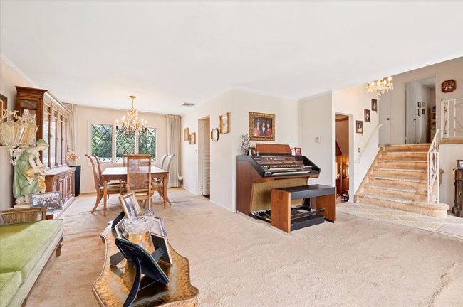 Living area featuring a chandelier, light carpet, stairs, and ornamental molding | Image 5