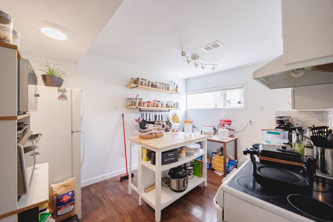 Kitchen featuring open shelves, freestanding refrigerator, dark wood-type flooring, and tasteful backsplash | Image 32