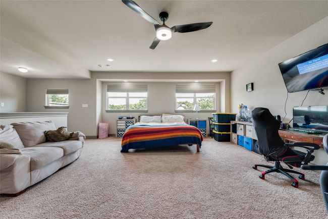 Carpeted bedroom featuring multiple windows, an office area, a ceiling fan, and recessed lighting | Image 32