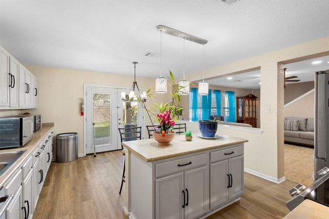 Kitchen with stainless steel microwave, light countertops, light wood-style flooring, and visible vents | Image 12