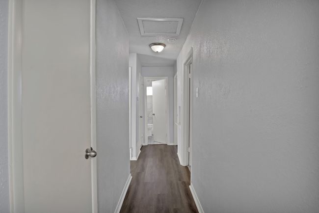 Corridor with visible vents, dark wood finished floors, baseboards, attic access, and a textured wall | Image 22