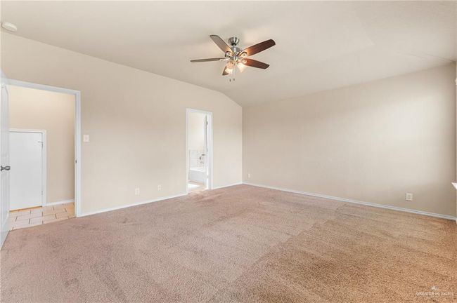 Carpeted empty room featuring ceiling fan and lofted ceiling | Image 11