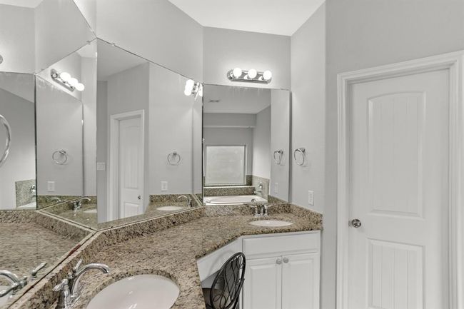 This Primary bathroom is complete with large mirrors, a vanity area, double sinks, granite countertops and backsplash. | Image 13