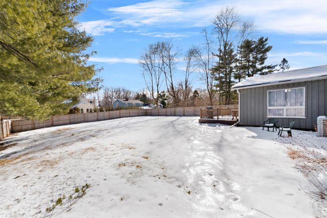 Yard covered in snow with fence and a deck | Image 38