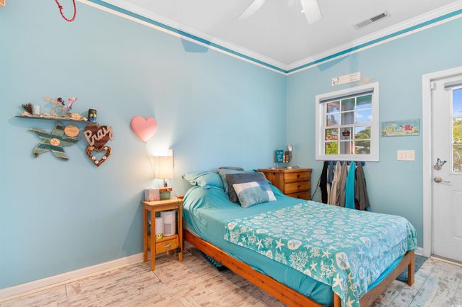 Bedroom with wood finished floors, ornamental molding, a ceiling fan, and baseboards | Image 16