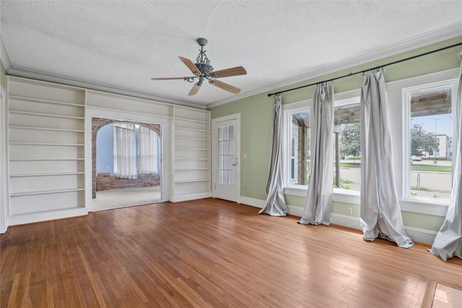 Spare room featuring a textured ceiling, crown molding, wood finished floors, baseboards, and a ceiling fan | Image 4