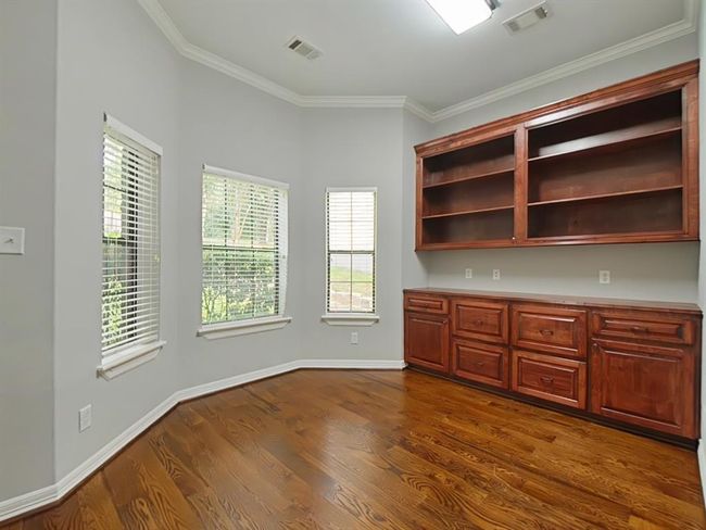 Discover the inviting home office just off the entrance, featuring elegant built-in cabinets and bookshelves. This room could also be used as a fourth bedroom with the closet that is included. | Image 6