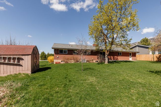 Back of property with a lawn, an outdoor structure, a chimney, and a shed | Image 40