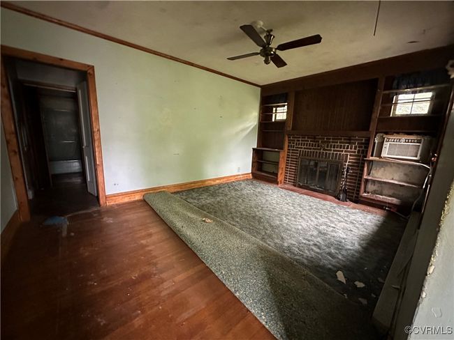 Unfurnished living room with a glass covered fireplace, a ceiling fan, baseboards, ornamental molding, and wood finished floors | Image 20