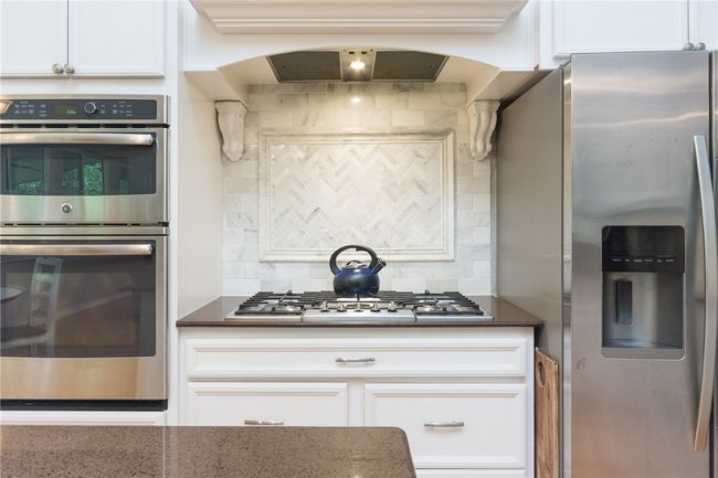Kitchen with stainless steel appliances, tasteful backsplash, white cabinets, and dark stone countertops | Image 6