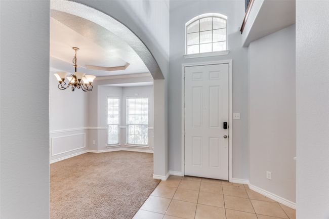 Foyer featuring arched walkways, a chandelier, light tile patterned floors, light carpet, and a raised ceiling | Image 4