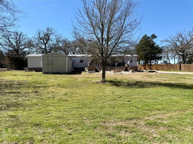 View of yard with a storage unit, fence, and an outdoor structure | Image 7