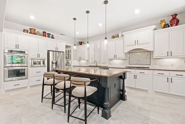 Boasting gorgeous pendant lighting, double ovens and so much more, the decadent kitchen is the heart of this stunning home. | Image 11