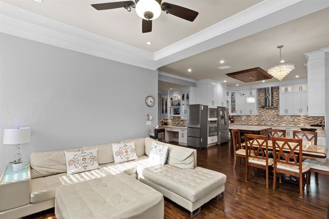 Living area featuring a ceiling fan, dark wood-type flooring, ornamental molding, and recessed lighting | Image 16