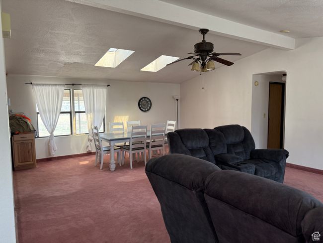 Carpeted living room featuring a skylight, baseboards, ceiling fan, and a textured ceiling | Image 5