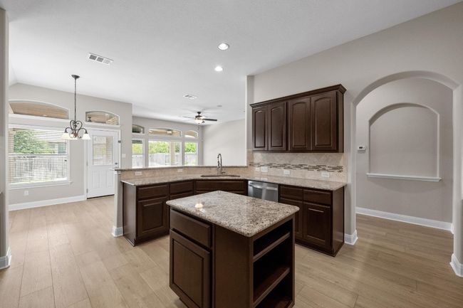 Kitchen featuring dishwasher, dark brown cabinets, tasteful backsplash, light wood finished floors, and recessed lighting | Image 8